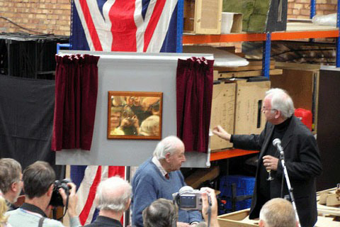 A brass plaque sits on a board with curtains that have just been opened sitting either side.